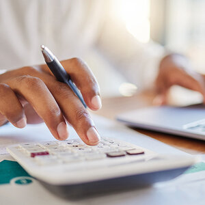 The hand of a businessman as he enters figures into a calculator The hand of a businessman as he enters figures into a calculator