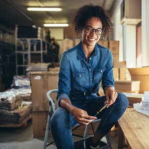An African American entrepreneur sits on a stepstool in her workshop. An African American entrepreneur sits on a stepstool in her workshop.