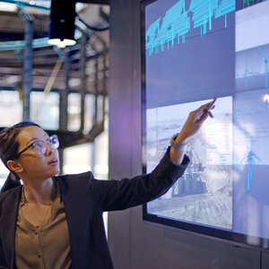 A woman pointing at a screen showing wind turbines. A woman pointing at a screen showing wind turbines.