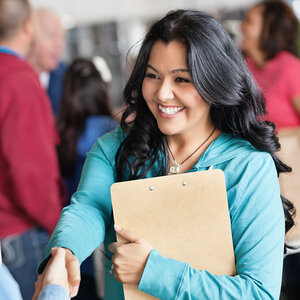 A woman in a light-blue blouse is smiling