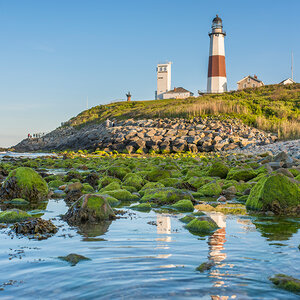 The image of a lighthouse is reflected in still water at low tide. The image of a lighthouse is reflected in still water at low tide.
