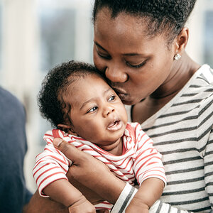 A mother kissing her infant on the forehead.
