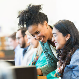 Two women working together look at a computer screen. Two women working together look at a computer screen.