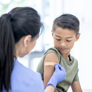 A child receiving a band-aid after getting a vaccine.