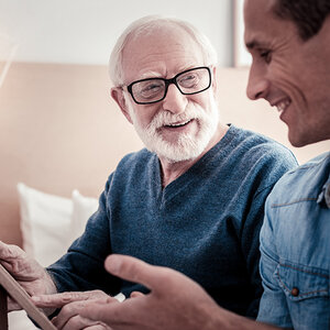 A white-haired, bearded man smiles at his younger heir A white-haired, bearded man smiles at his younger heir