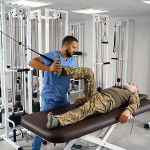 A man in a military uniform performing stretched with the guidance of a physician. A man in a military uniform performing stretched with the guidance of a physician.