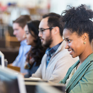 Diverse adults sitting in front of computer screens. Diverse adults sitting in front of computer screens.