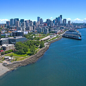 A shoreline with greenspace and recreation areas with a city skyline in the background - Seattle Washington.
