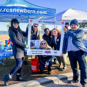 A group of volunteers in winter clothes pose for social media photos.