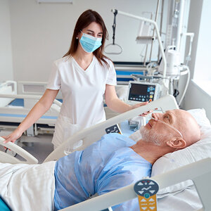 A nurse attends to her patient lying on a hospital bed.