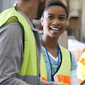 A woman in a safety vest turns to talk to her coworker. A woman in a safety vest turns to talk to her coworker.