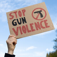 A hand holding a sign that reads: Stop Gun Violence. A hand holding a sign that reads: Stop Gun Violence.