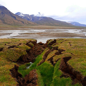 An arctic landscape with mountains at a distance and thawed permafrost in the foreground. An arctic landscape with mountains at a distance and thawed permafrost in the foreground.
