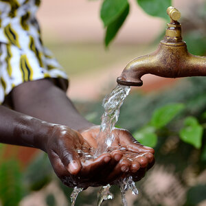 A closeup image of a child’s hands cupped to hold water pouring from a tap. A closeup image of a child’s hands cupped to hold water pouring from a tap.