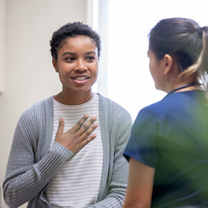 An African American woman, talking to her female doctor, holds her hand to her chest to emphasize a point. An African American woman, talking to her female doctor, holds her hand to her chest to emphasize a point.