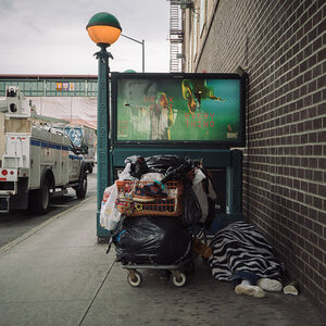 A homeless person laying in front of a subway station.