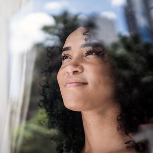 An African American woman looks out a window.