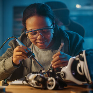 A Black woman solders.