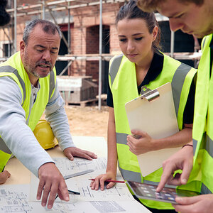 An instructor reviews blueprints with his students on a job site. An instructor reviews blueprints with his students on a job site.