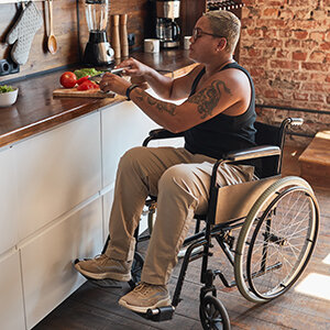 A female veteran in a wheelchair prepares a meal in an accessible kitchen.