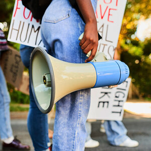 A close up of a megaphone being carried by a woman at a protest march.