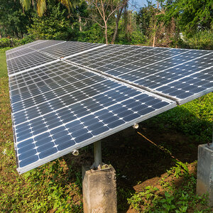 A row of solar panels in a field carved from the forest. A row of solar panels in a field carved from the forest.
