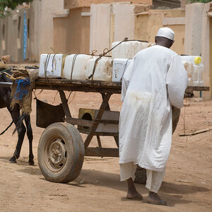 A man in Sudan delivering water by donkey cart.