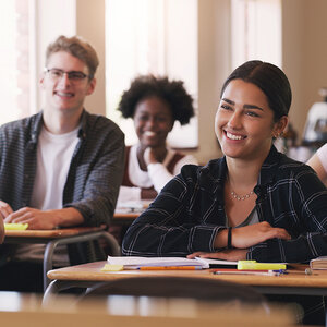 Three high school students seated at their desks in a classroom. Three high school students seated at their desks in a classroom.