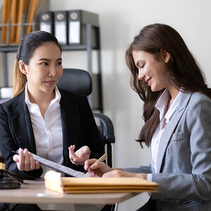 A female lawyer shows a document to her female client in an office.