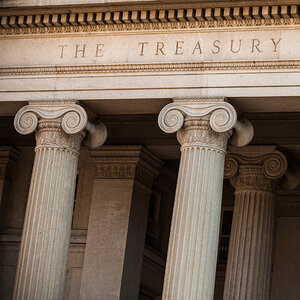 The façade of a neoclassical government building with the words The Treasury in the frieze. The façade of a neoclassical government building with the words The Treasury in the frieze.