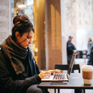 A woman working on a laptop in a cafe. A woman working on a laptop in a cafe.