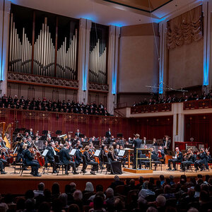 An audience watches a symphony orchestra perform in a beautiful concert hall. An audience watches a symphony orchestra perform in a beautiful concert hall.
