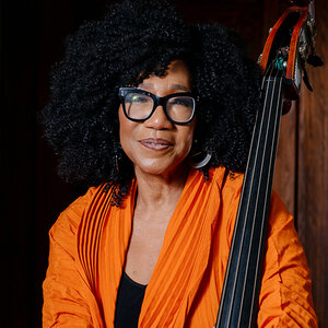 An African American woman wearing orange holds an upright bass—a photo of Marion Hayden. An African American woman wearing orange holds an upright bass—a photo of Marion Hayden.