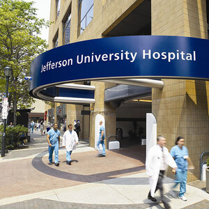 People walk past the entryway of a hospital with a sign that reads Jefferson University Hospital. People walk past the entryway of a hospital with a sign that reads Jefferson University Hospital.