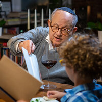 A Jewish grandfather helps his grandson during a Passover Seder. A Jewish grandfather helps his grandson during a Passover Seder.