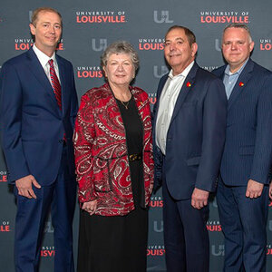 Three men and a woman pose for a photo at a public event. Three men and a woman pose for a photo at a public event.