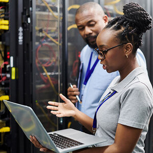 A man and woman looking at a laptop computer in a data center. A man and woman looking at a laptop computer in a data center.