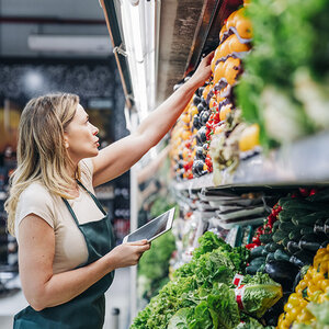 A woman stocking the produce in a store. A woman stocking the produce in a store.