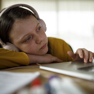 A child with her head on her desk in a virtual class. A child with her head on her desk in a virtual class.
