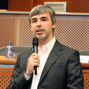 A man in a business suit with no tie speaks into a microphone – an image of Larry Page.