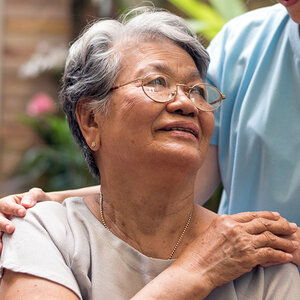 An elderly woman is being comforted by her caregiver.
