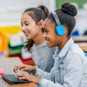 Two smiling girls in a computer lab collaborate on a project. Two smiling girls in a computer lab collaborate on a project.