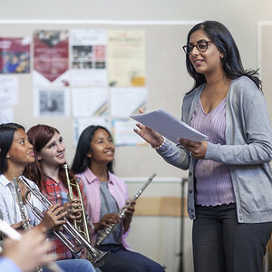A music teacher instructs her diverse class of band students. A music teacher instructs her diverse class of band students.