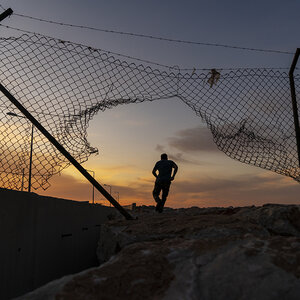 A refugee man running behind a fence.