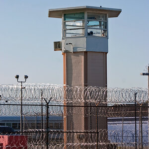 The guard tower of a prison surrounded by fencing and barbed wire. The guard tower of a prison surrounded by fencing and barbed wire.
