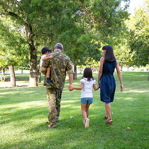A uniformed veteran and his family walk in a park. A uniformed veteran and his family walk in a park.