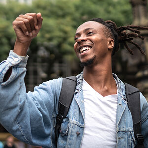 An African American student raises his arm in celebration.