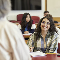 A college student sitting in class, smiling at her professor. A college student sitting in class, smiling at her professor.