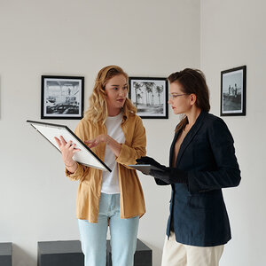 Two gallery workers discussing an art piece. Two gallery workers discussing an art piece.
