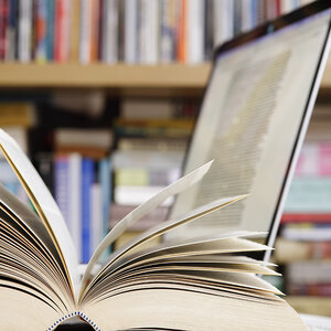 An open book on top of a laptop. An open book on top of a laptop.